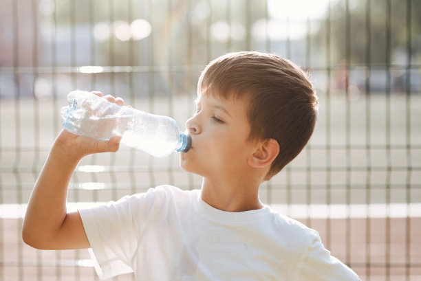 夏天，可爱的孩子在街上用瓶子喝水图片下载