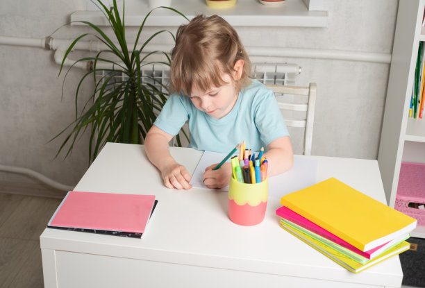 回到学校。女孩坐在有书和笔记本的桌子旁做作业。图片下载