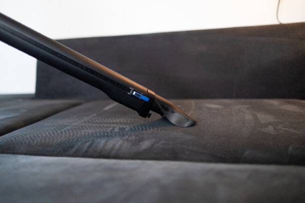 清洁服务公司员工用专业设备清除公寓家具上的污垢。女管家手臂清洗沙发，用吸尘器清洗靠近图片下载