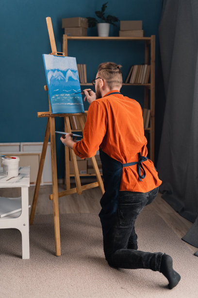 男艺术家在明亮的家庭工作室里画画。一名男子在画室用毛笔在画架上作画图片下载