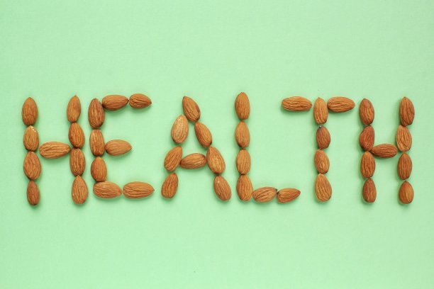 杏仁排列成绿色背景上的“健康”字样。健康饮食，生食饮食，营养，素食的理念。蛋白质有机干粮、谷类食品。全国坚果日。文本复制空间图片下载