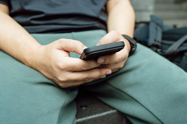 男子在玩手机游戏。玩电子游戏的男孩拿着SmartphoneÂ工作的移动设备。手机技术电子商务概念图片下载