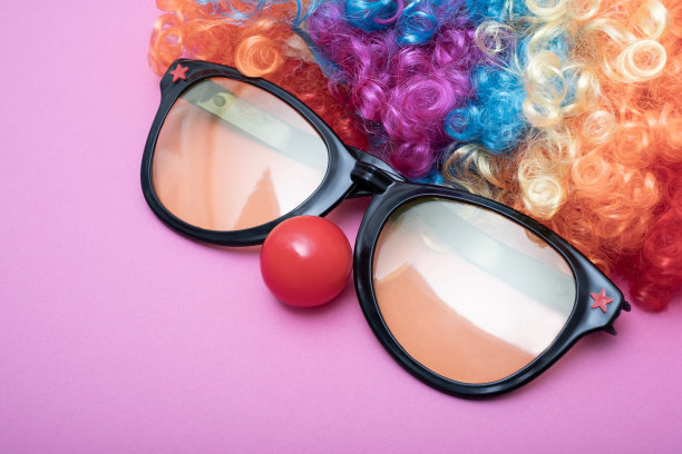 滑稽派对概念脸形成与眼镜镜片。彩虹小丑假发集和红色小丑鼻子像一个脸，蓬松的非洲合成Cosplay动漫花式假发节日背景图片下载