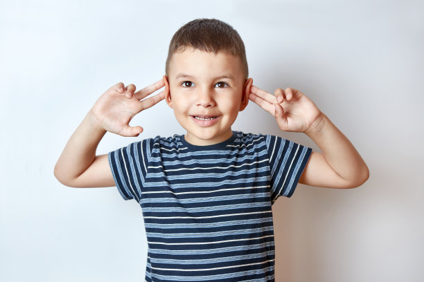 快乐的小男孩带着微笑双手弯着耳朵。图片下载