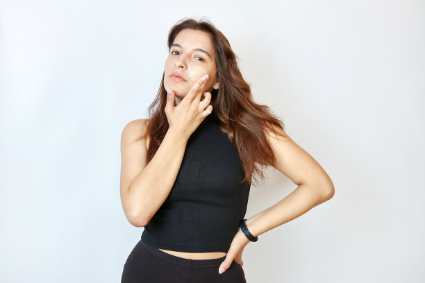 美丽的女孩在脸上涂粉底。图片下载