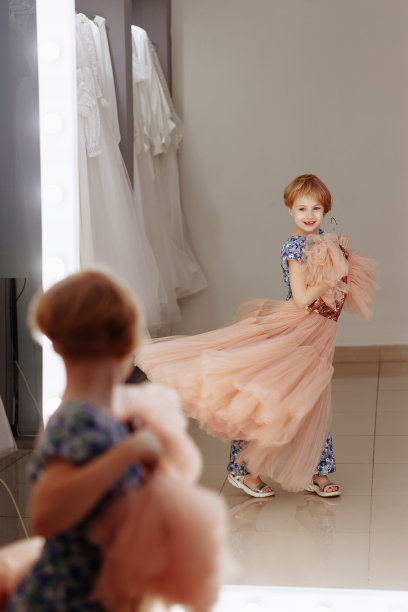 一个小女孩在镜子前挑选衣服。图片下载