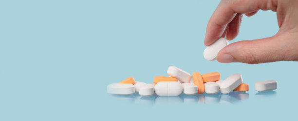 手和蓝色桌子上的白色药片，医药图片下载