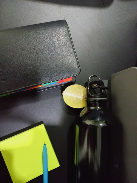 现代黑色办公桌与办公笔记本。日记表。钢笔和黄色的纸贴纸。绿色成熟酸橙和黑色铝运动瓶图片下载