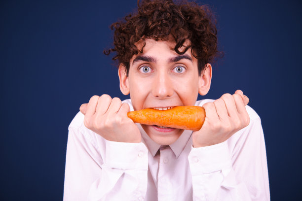 素食主义。有趣的情绪化的家伙吃胡萝卜。图片下载