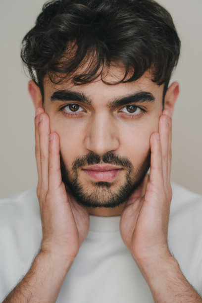 一个英俊的年轻人在刮胡子前仔细端详自己的脸。特写肖像。带来有吸引力的图片下载