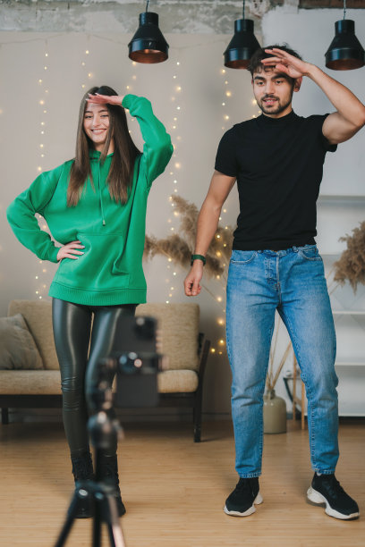 一对白人夫妇用智能手机制作社交媒体内容视频，在家里一边跳舞一边录制。写博客。有创造力的人。互联网技术。图片下载