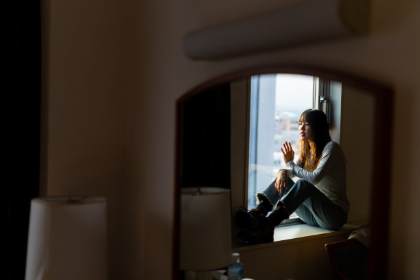 冬日夕阳下，年轻的亚洲女子坐在卧室的窗边。图片下载