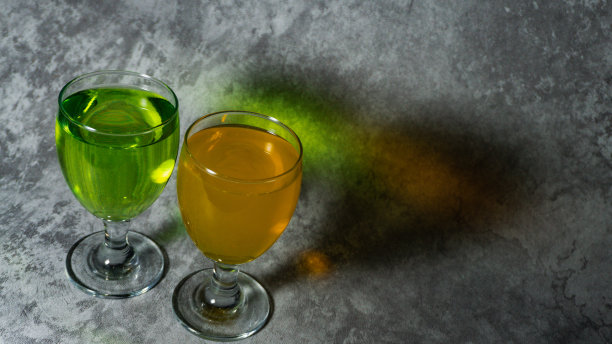 用玻璃杯盛橘子糖浆和甜瓜糖浆。糖浆是绿色和橙色的。图片下载