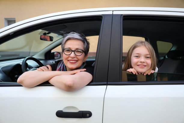 一位快乐而随意的母亲和她的小女儿坐在车里。他们是一个美丽而充满爱的家庭，一起度假或度假。图片下载