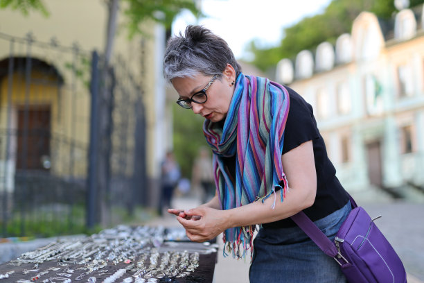 一位兴高采烈的老年妇女在跳蚤市场购买古董珠宝。她喜欢街市的文化和传统。图片下载
