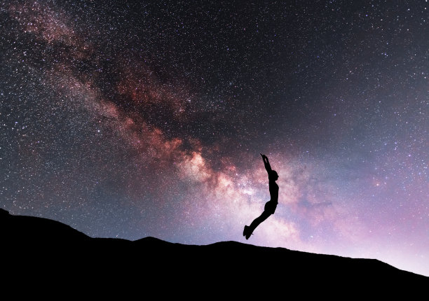 女人的剪影在夜晚跳舞健身，在明亮的银河背景下。图片下载