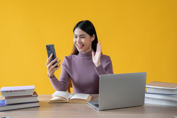 一位美丽的亚洲女性正在她的办公桌前与她的朋友进行视频通话。图片下载