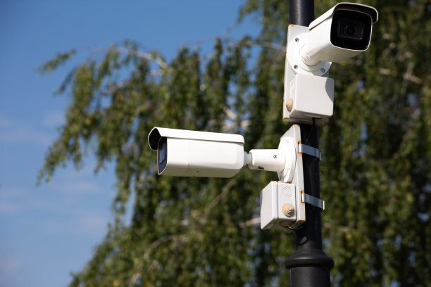 杆子上的两个白色监控摄像头朝不同的方向望去图片下载