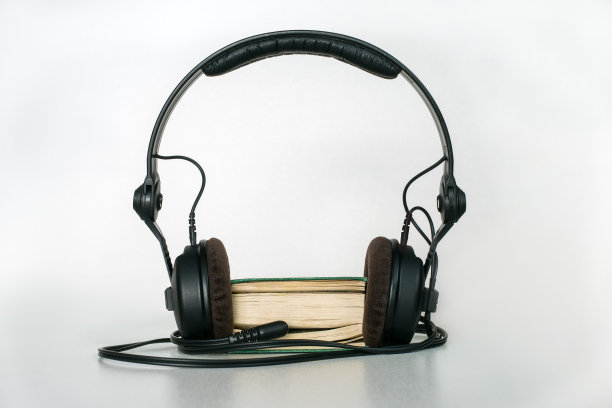 带有耳机和迷你插孔插头的袖珍书，在浅色背景的书页之间插入。有声书的概念图片下载