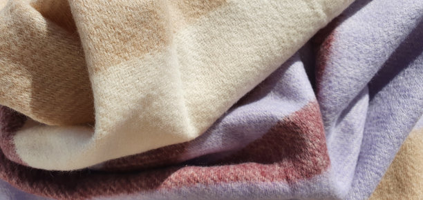 温暖的围巾背景。几何图案的羊毛围巾。米色-丁香条纹围巾纹理。柔软的羊毛保暖织物。柔软的衣服。毛衣折叠。图片下载