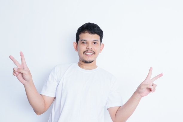 一个穿着休闲白衬衫的年轻人对着镜头微笑。度假旅游理念图片下载