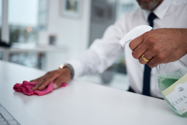人员，双手和清洁桌子在办公室用布，喷雾瓶和卫生，以确保病毒的安全。特写工人擦拭脏桌子，表面和卫生的灰尘，消毒和细菌的风险图片下载