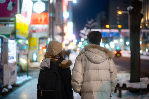一对亚洲夫妇在冬夜一起走在城市街道上。图片下载