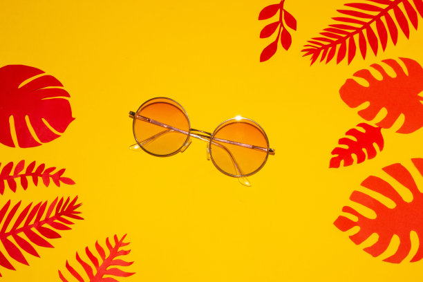 太阳镜在一个黄色的背景周围的边缘的背景排热带树叶，创造性的异国情调的夏季概念图片下载