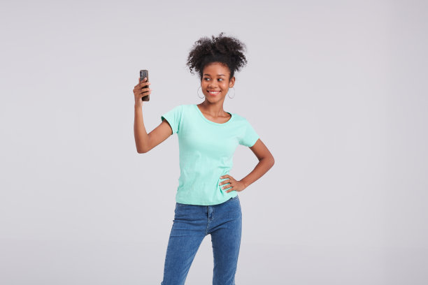 移动时尚达人:泰裔美国女性用智能手机在工作室摆姿势图片下载