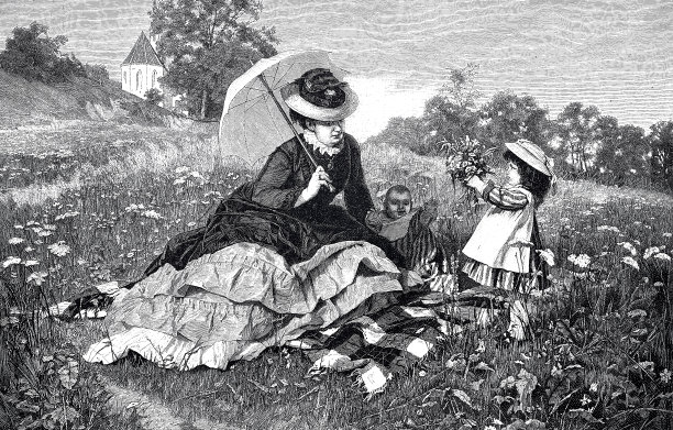 妈妈带着两个孩子在草地上野餐图片下载