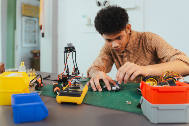亚洲年轻人组装机器人汽车，专注于机器人技术，组装机器人机器人开发智能机器人，机械系学生组装救援机器人汽车。监视机器人。图片下载