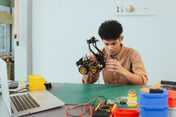 亚洲年轻人组装机器人汽车，专注于机器人技术，组装机器人机器人开发智能机器人，机械系学生组装救援机器人汽车。监视机器人。图片下载