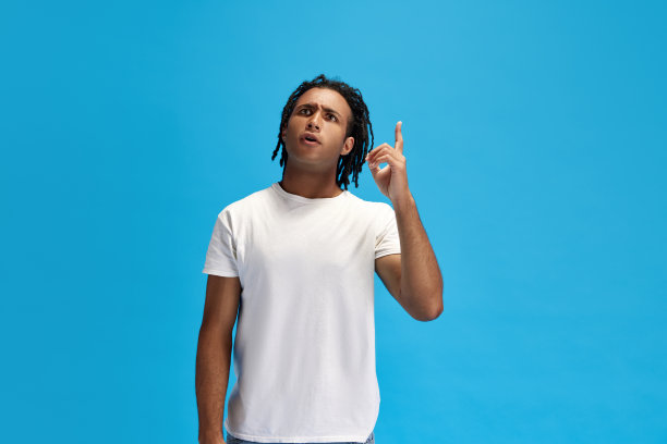 穿着休闲服的年轻人举起手指，在蓝色的工作室背景下，在头脑中创造想法图片下载