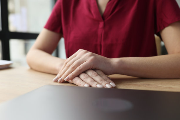 女性的手放在桌子上，前面是一台关闭的笔记本电脑图片下载