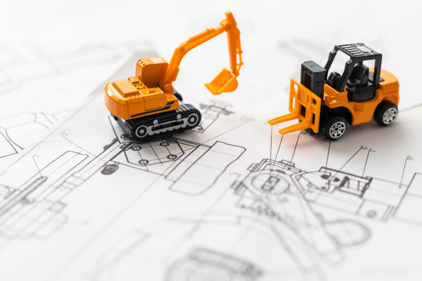 在蓝图建筑项目上的挖掘机或卡车的小型复制品的俯视图与复制空间。图片下载