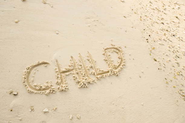 “孩子”这个词写在沙滩上。在沙滩上画画。用沙滩上的沙子写字。图片下载