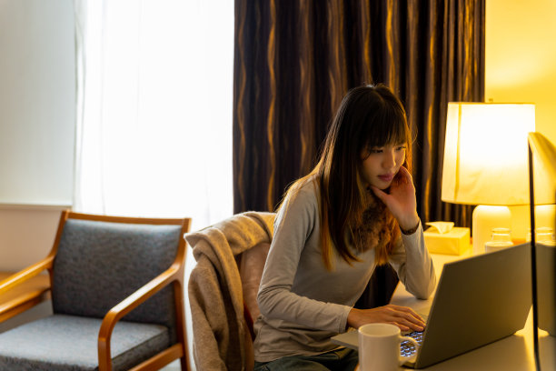 在酒店房间用笔记本电脑工作的亚洲妇女。图片下载