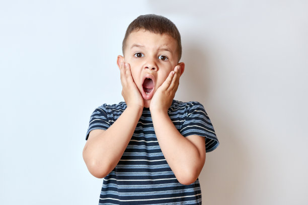 小男孩迷人地把手放在脸颊上，嘴巴张得大大的。图片下载