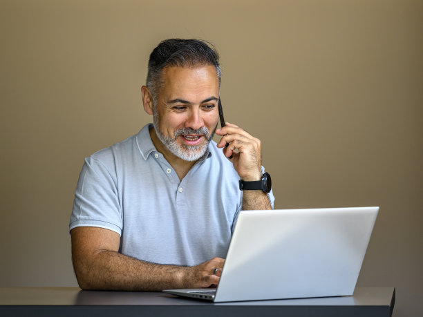 一个面带微笑的商人，拿着笔记本电脑用手机聊天图片下载