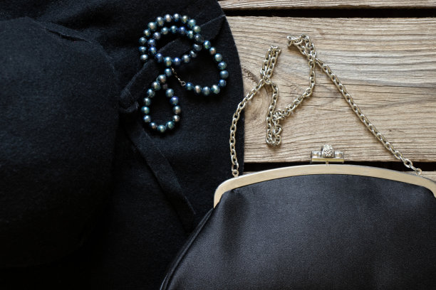 黑色女性的帽子和黑色晚装包和木桌上的一些珍珠珠子，时尚和潮流，美丽图片下载