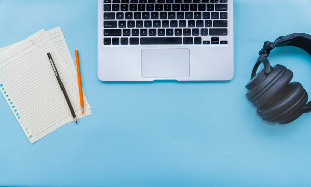 学生的蓝色桌子，笔记本电脑，黑色耳机，纸笔记和铅笔，俯视图图片下载