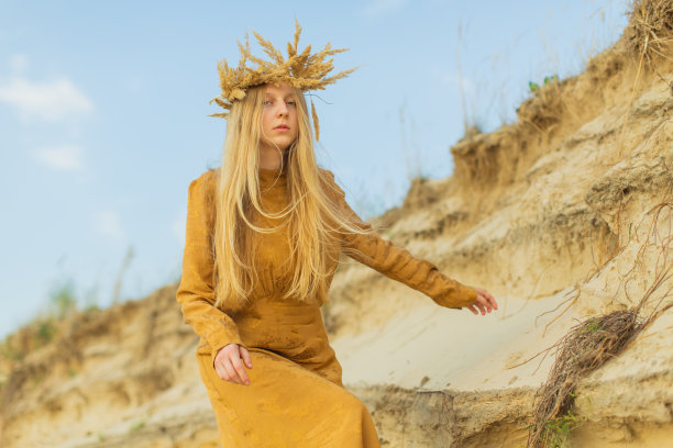 自然美景。穿黄色衣服的金发女人躺在河岸上。夕阳的光。夏天的一天。长头发的。沙子。图片下载