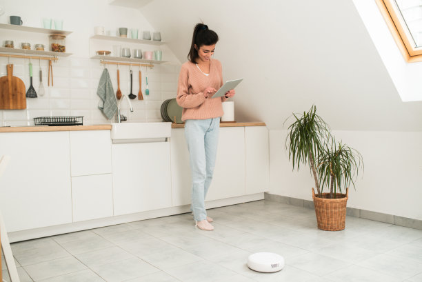 一个美女用平板电脑设置她的智能吸尘器图片下载