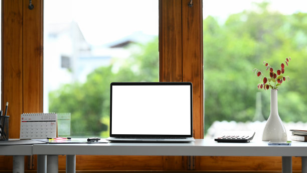 家庭办公室内部，空白屏幕的笔记本电脑和白色桌子上的办公用品。图片下载