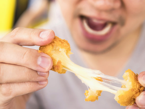 男人要吃粘乎乎的炸奶酪球。照片聚焦于奶酪球图片下载