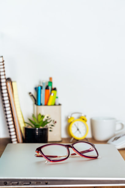 封闭的笔记本放在房间的桌子上，女士的眼镜放好，竖着拍照、复印的空间图片下载