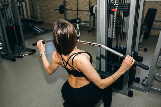 漂亮的长发女孩正在健身房做举重训练。私人健身教练正在锻炼肌肉。运动动机健康的生活方式。女性身体锻炼。图片下载