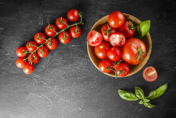 新鲜的圣女果，黑色背景，绿叶。图片下载