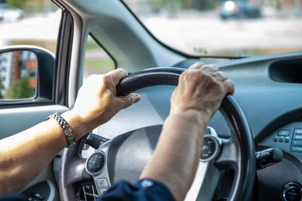 白人老妇，77岁，开着车。女人的手放在汽车方向盘上。图片下载
