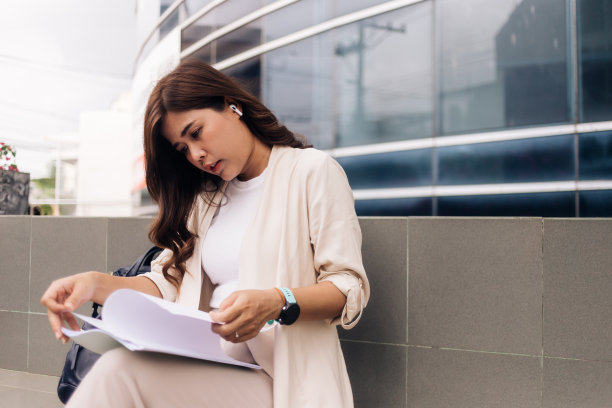 漂亮的年轻女商人坐在户外的楼梯上写笔记本图片下载